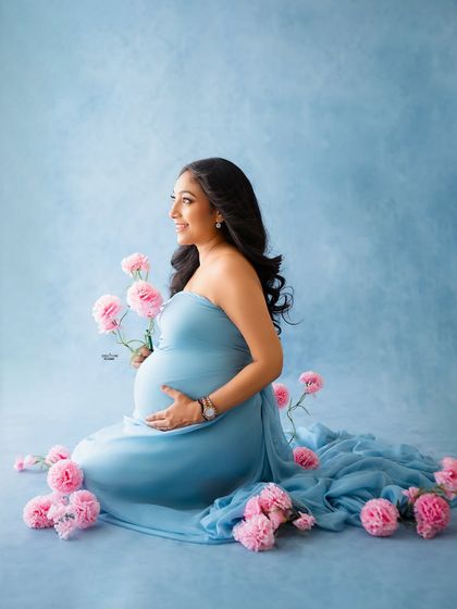 A lovely seated portrait with a blue tossing fabric gown, surrounded by pink carnations. The color combination is so unique and beautiful.