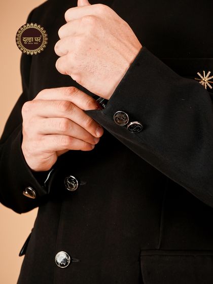 Details that define elegance. A close-up on the sleeve of a black suit, showcasing the sleek buttons and fine tailoring.