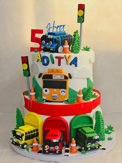 All aboard the Tayo bus. This two-tier cake features the friendly little bus and his friends, complete with their colorful garages, traffic cones, and signals for a fun city adventure.