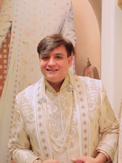 Styling a groom's look with a pearl necklace and an exquisitely embroidered sherwani. Accessories are key to completing the perfect wedding ensemble.
