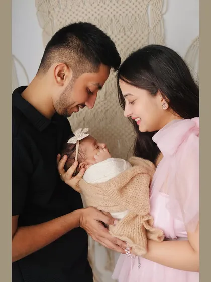 The first family portrait is a memory to hold onto forever. Here, new parents gaze lovingly at their swaddled baby, capturing that initial bond in a simple, beautiful setting.