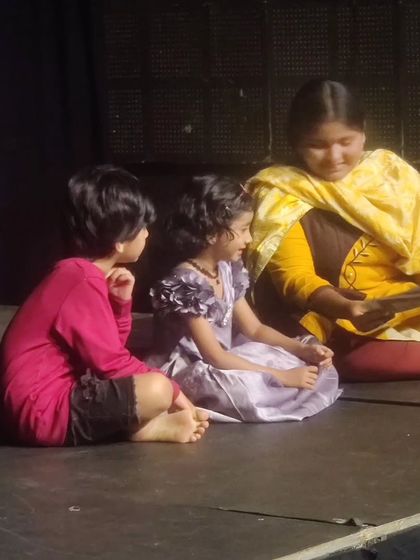 A tender moment on stage where an older student reads to the younger ones. Our classes foster a sense of mentorship and support among the children.