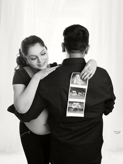 A creative and sweet black and white shot, with the mom-to-be showing the sonogram pictures on her partner's back. It's a unique way to incorporate the baby's first photos into the session.