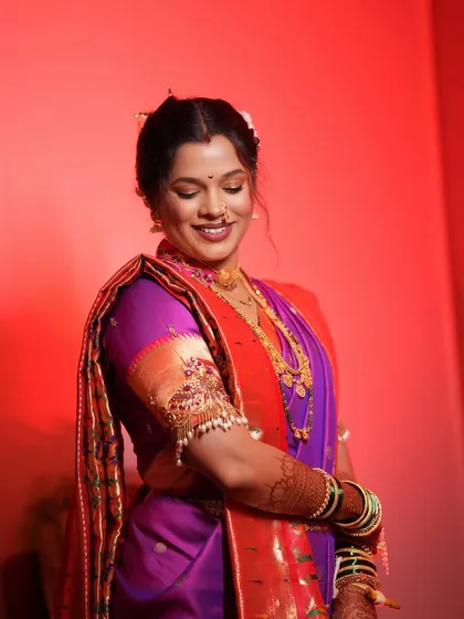 A candid moment of a happy bride in her purple and orange Paithani saree. The soft glam makeup and gentle smile capture the joy of her special day.