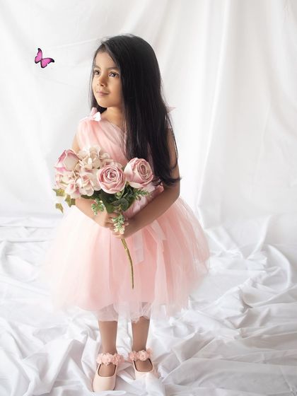 Holding a bouquet of flowers, this birthday girl looks like she's stepped out of a storybook. A little butterfly adds a whimsical touch.