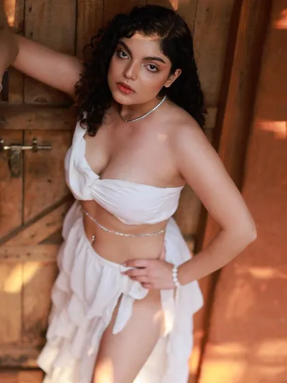 An 'Apsara' or celestial nymph concept, shot at the beautiful Aura Kalari in Bangalore. The white, flowing outfit and the model's pose against the wooden door create a mythical and ethereal feel.