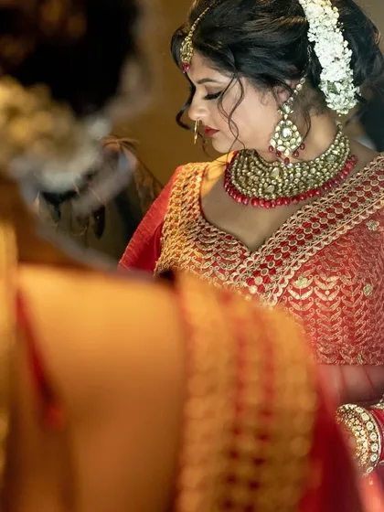 A close-up of the bride's getting-ready process, with a focus on her intricate jewelry and the beautiful floral arrangement in her hair.