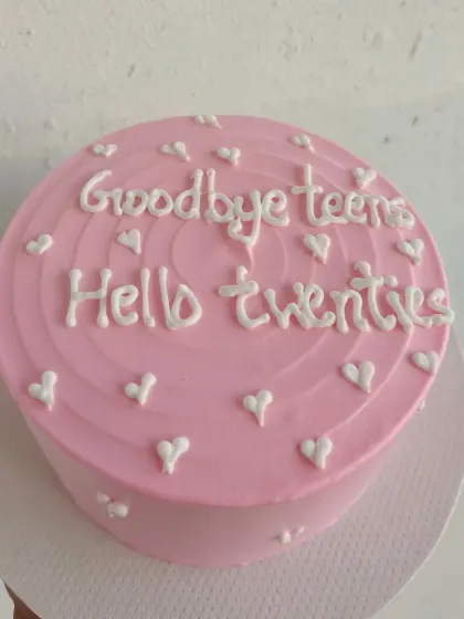 A pink minimalist cake celebrating the transition from teens to twenties with the message "Goodbye teens, Hello twenties."