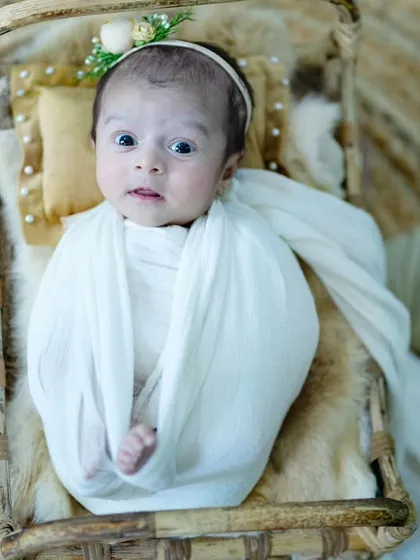 Look at that expressive face. This newborn is taking in the world from the comfort of a cozy, boho-themed basket setup.