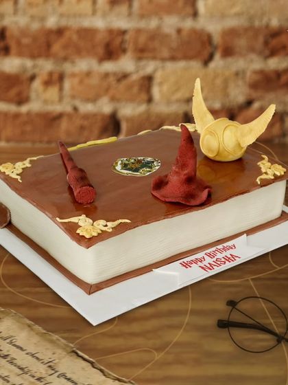 A magical Harry Potter spellbook cake. This incredibly detailed cake looks just like a real book, complete with a wand, the Sorting Hat, and a Golden Snitch.