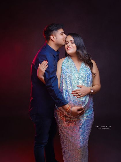 A tender moment between a couple, highlighted by colorful studio lighting. The sequined gown adds a touch of glamour and celebration.