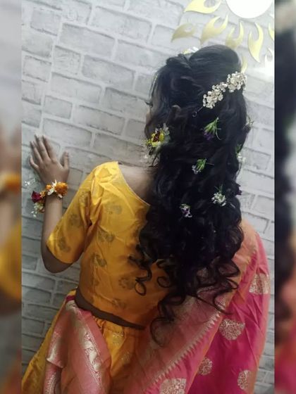 Another angle of the Haldi hairstyle, showing the placement of the hair accessories and the texture of the curls. Our students practice creating durable styles that look beautiful from every view.