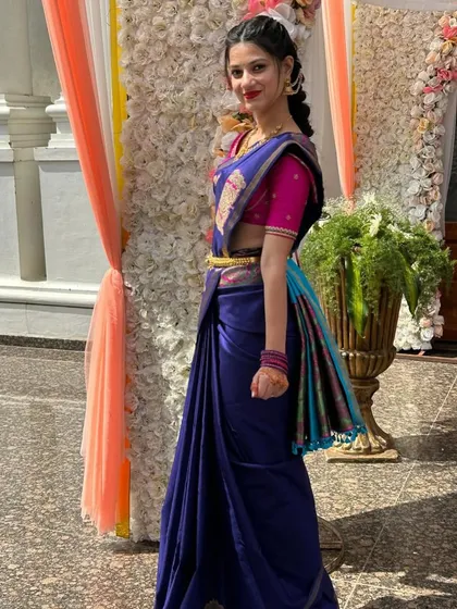 A client in a royal blue saree with a multi-colored border, paired with a contrasting bright pink blouse.