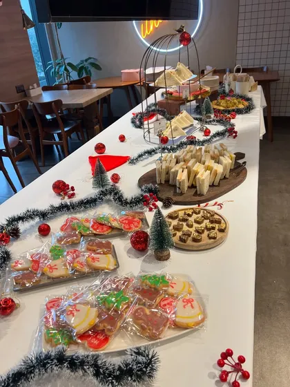 A full view of the high tea buffet we set up for a corporate Christmas party. The table was filled with festive treats, including sandwiches, cookies, and pastries, all surrounded by holiday decorations.