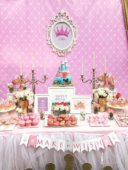 A royal dessert table for a princess birthday. The setup featured castle turrets, a royal crown emblem, and a "Make a Wish" banner for a fairytale celebration.
