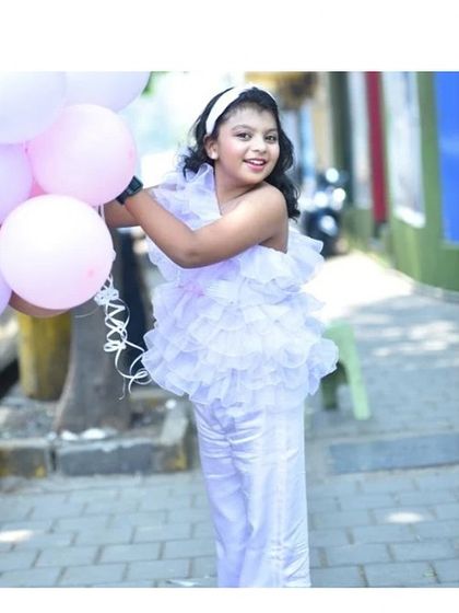 For the older girls who love drama. This all-white outfit features a top covered in organza ruffles paired with sleek satin pants, perfect for a stylish birthday celebration.