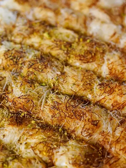 A close up of our perfectly golden Kunafa. This classic Middle Eastern dessert features a sweet cheese filling topped with crispy shredded pastry.