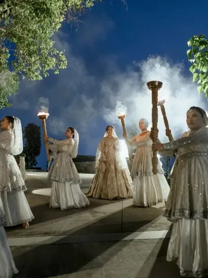 A grand and theatrical bridal entry, with dancers holding torches lighting her path.