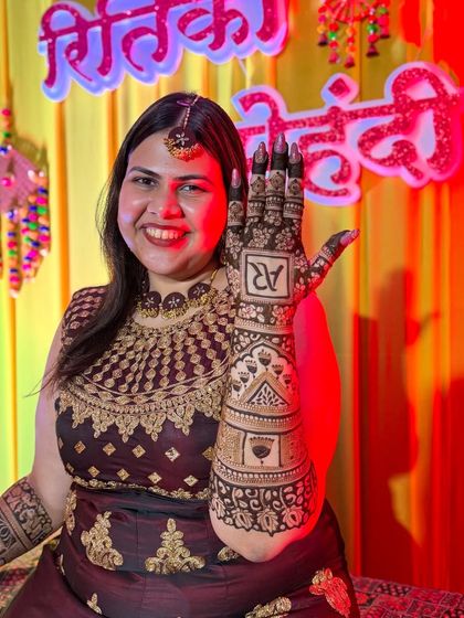 A close-up of the bride showing off the back of her hand, featuring a beautifully designed monogram of her and her partner's initials.
