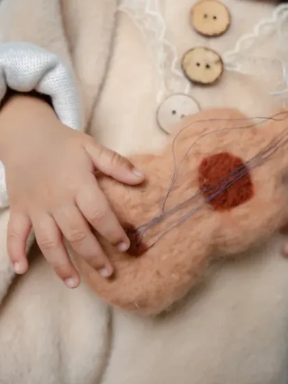 From newborn snuggles to two-month giggles, every detail is precious, like these tiny hands on a felt guitar.