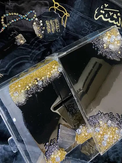 This luxurious black, gold, and silver combo set is a popular choice for a bridal gift. It includes a premium velvet prayer mat, a personalized acrylic Quran box, a resin Quran stand (rehal), a crystal tasbeeh, and a matching car hanging.