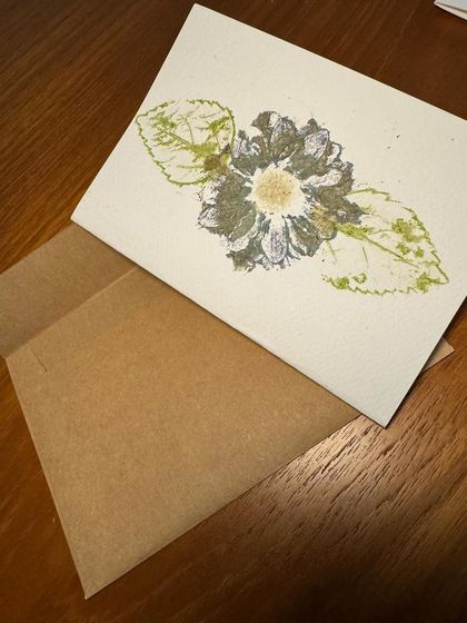 A close-up of a greeting card with a detailed flower and leaf print. The flower pounding technique captures the texture and shape of the botanicals beautifully.