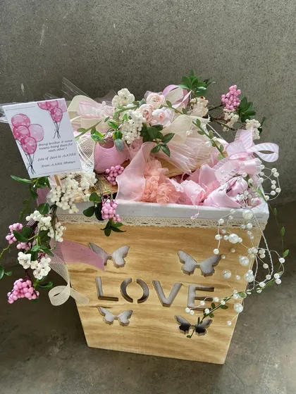 A gift of love, literally. This charming wooden planter box with a "LOVE" cutout is filled with delicate pink and white gifts, perfect for a birth announcement, a bridal shower, or a romantic gesture.