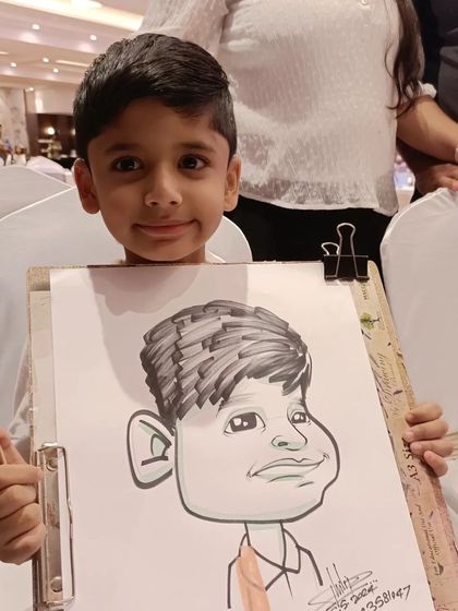 A young boy proudly holding up his caricature. It's a great confidence booster for kids.