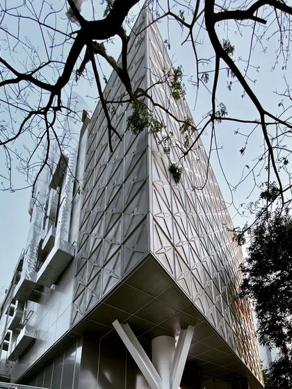 A corner view of the MAP museum's facade, showing the intricate, three-dimensional pattern of the stainless steel panels. This "skin" is not just decorative; it controls light and reflects the sky, changing its appearance throughout the day.