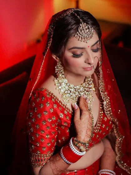 A close-up of a bride in her red wedding outfit, highlighting her kundan jewelry.