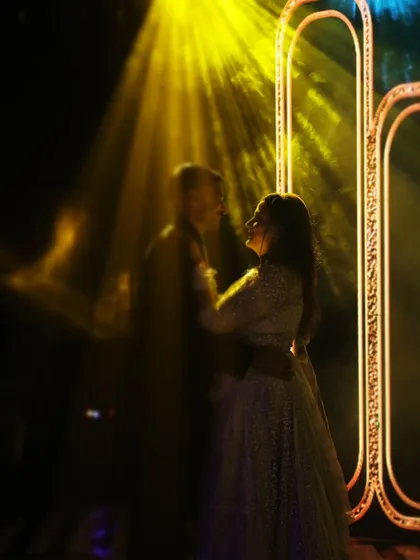 An artistic, blurry shot of the couple sharing a slow dance under a spotlight, creating a dreamy and romantic mood.