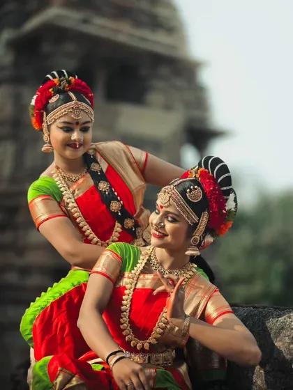 An intimate, smiling moment between two dancers in their full traditional attire, showcasing the human side of this ancient art form.