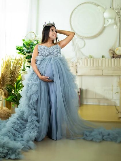 A wide shot showcasing a magnificent light blue gown in our studio with classic architectural elements. The long train fills the space, creating a truly grand portrait.