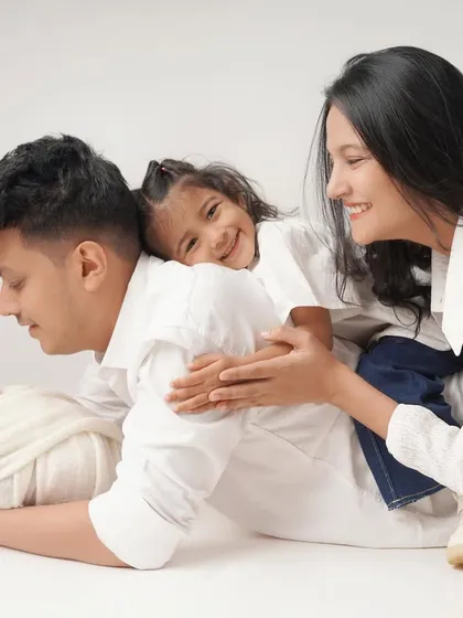 The complete family portrait, showing mother, father, big sister, and newborn baby sharing a beautiful, connected moment together.