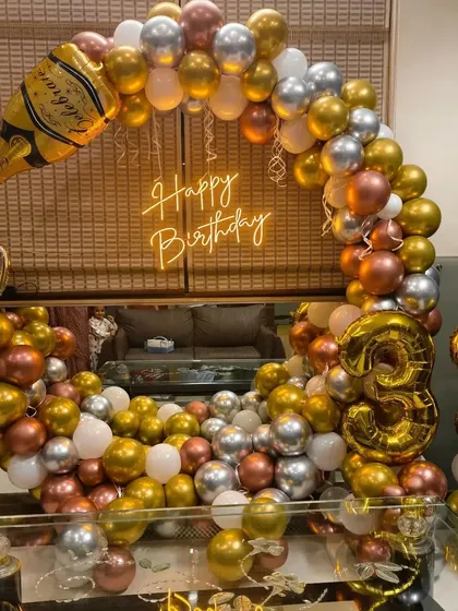 A fun 33rd birthday setup with a champagne theme. The balloon arch is accented with large foil balloons of a champagne bottle and beer mug.