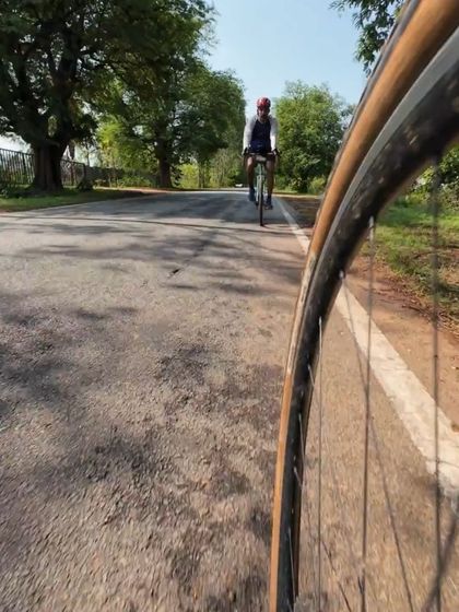 A low-angle shot from the wheel of a bike, looking towards an approaching rider. A creative perspective on the simple joy of a Sunday ride.