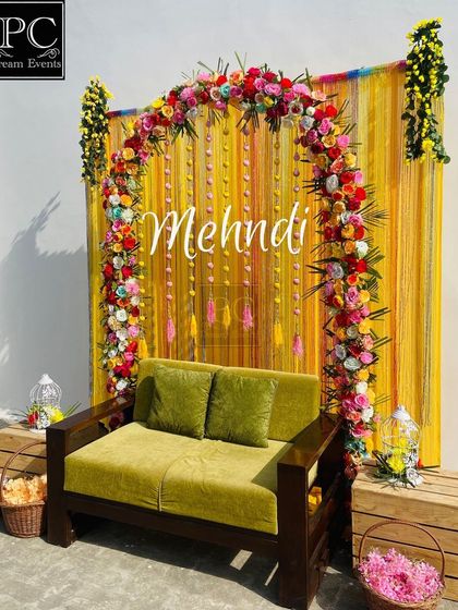 A full view of the sunny Mehndi seating area, complete with decorative birdcages and baskets of flowers on the side.