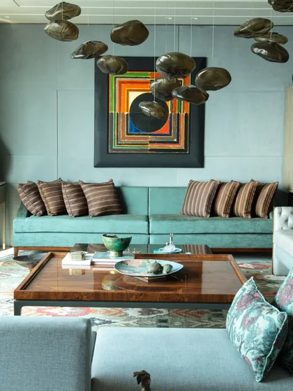 The living room at 'The 42, Kolkata', showcasing a custom-designed coffee table and a teal sofa. The space is a testament to artful living, with every piece carefully selected to tell a story.