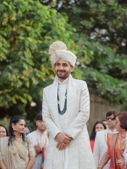 The groom's happy and proud expression as he waits for his bride at the altar.