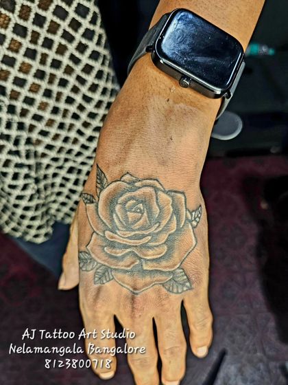 A fully shaded rose tattoo on the back of the hand, a classic design that never goes out of style.