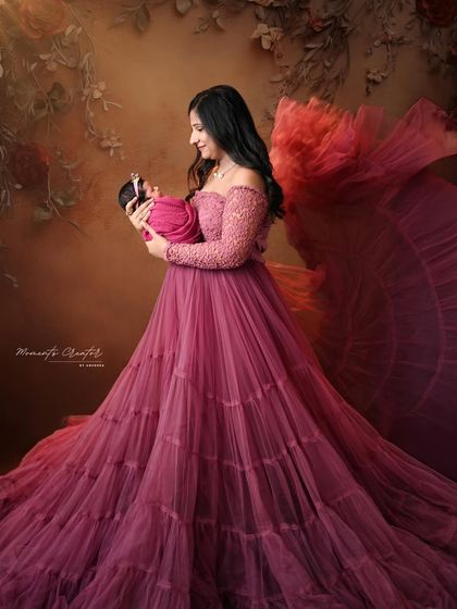 A dramatic and beautiful portrait of a mother holding her newborn. The flowing fabric of her gown adds a sense of movement and artistry to this special moment.