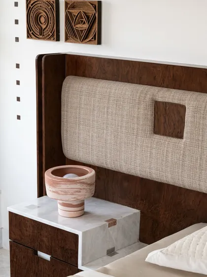 Detail of a custom bedside table in burl wood with a marble top. The pixelated marble support and woven details on the headboard showcase our love for mixing textures and geometric forms.