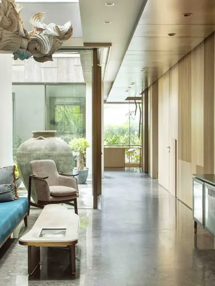 The ground floor family lounge corridor, featuring a custom sideboard and fluted wood paneling. The long, linear space is designed as a gallery for art and leads the eye towards the sunlit courtyard.