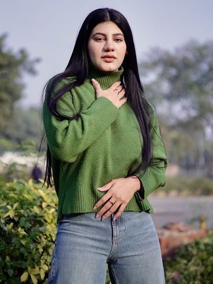 A medium shot of the model in a green sweater, with a focus on her expressive pose.