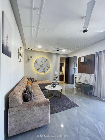A wide view of the KVK Camellia living room, showcasing the L-shaped sofa and the backlit marble wall art. The design is clean, modern, and comfortable.