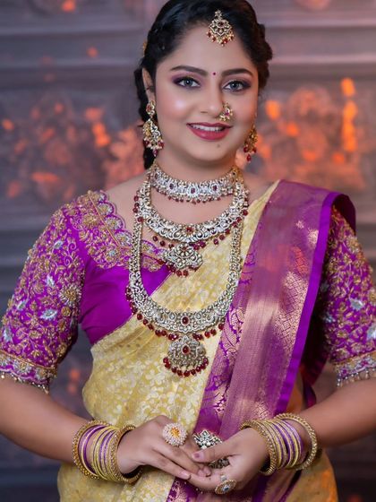 This bride is wearing a stunning Kundan set with ruby-colored stones. The jewellery beautifully complements her yellow and purple saree.