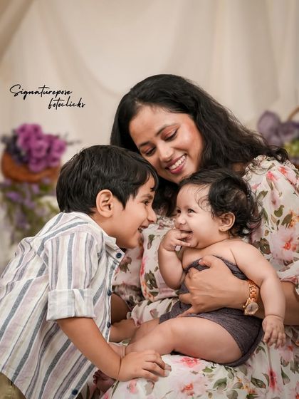A candid moment of interaction between a mother, her son, and her baby, full of smiles and genuine affection.