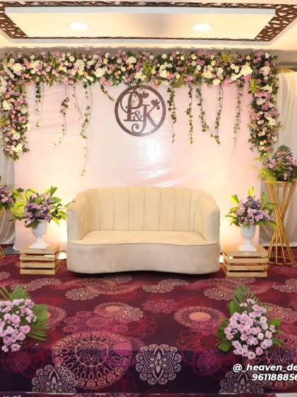 A full view of our personalized engagement stage, featuring the couple's monogram. The clean white backdrop is framed by a garland of pastel flowers and trailing ivy, creating a soft and romantic ambiance.