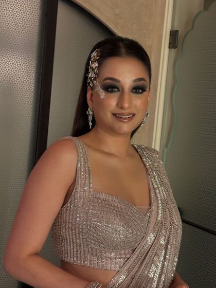 A sleek and modern look for a fashion event. The hair is styled straight and tucked behind one ear, with a dramatic silver accessory and smokey eye makeup completing the look.