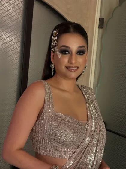 A sleek and modern look for a fashion event. The hair is styled straight and tucked behind one ear, with a dramatic silver accessory and smokey eye makeup completing the look.